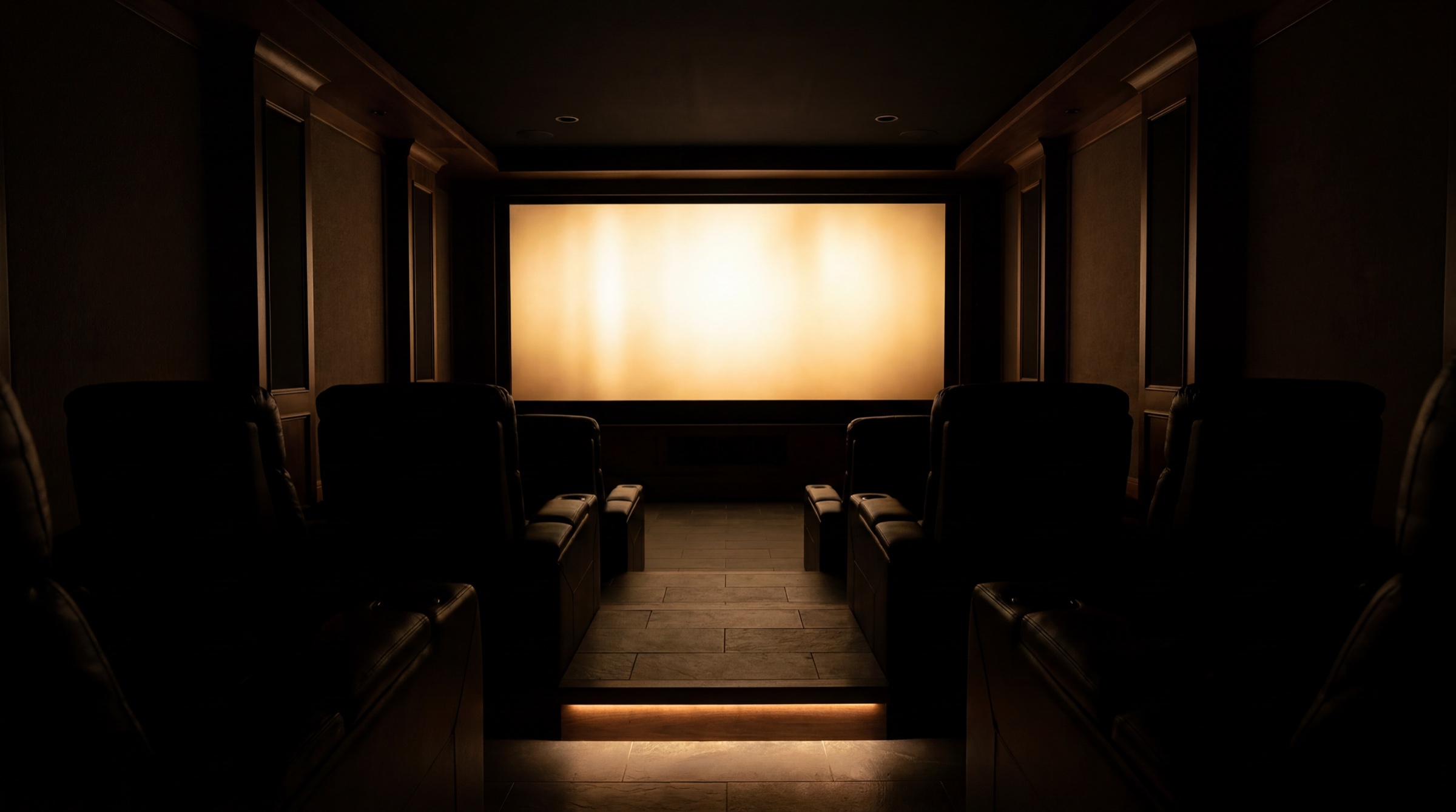 A private home theater with the screen lit and rows of seating, wired by Curt's Audio Video